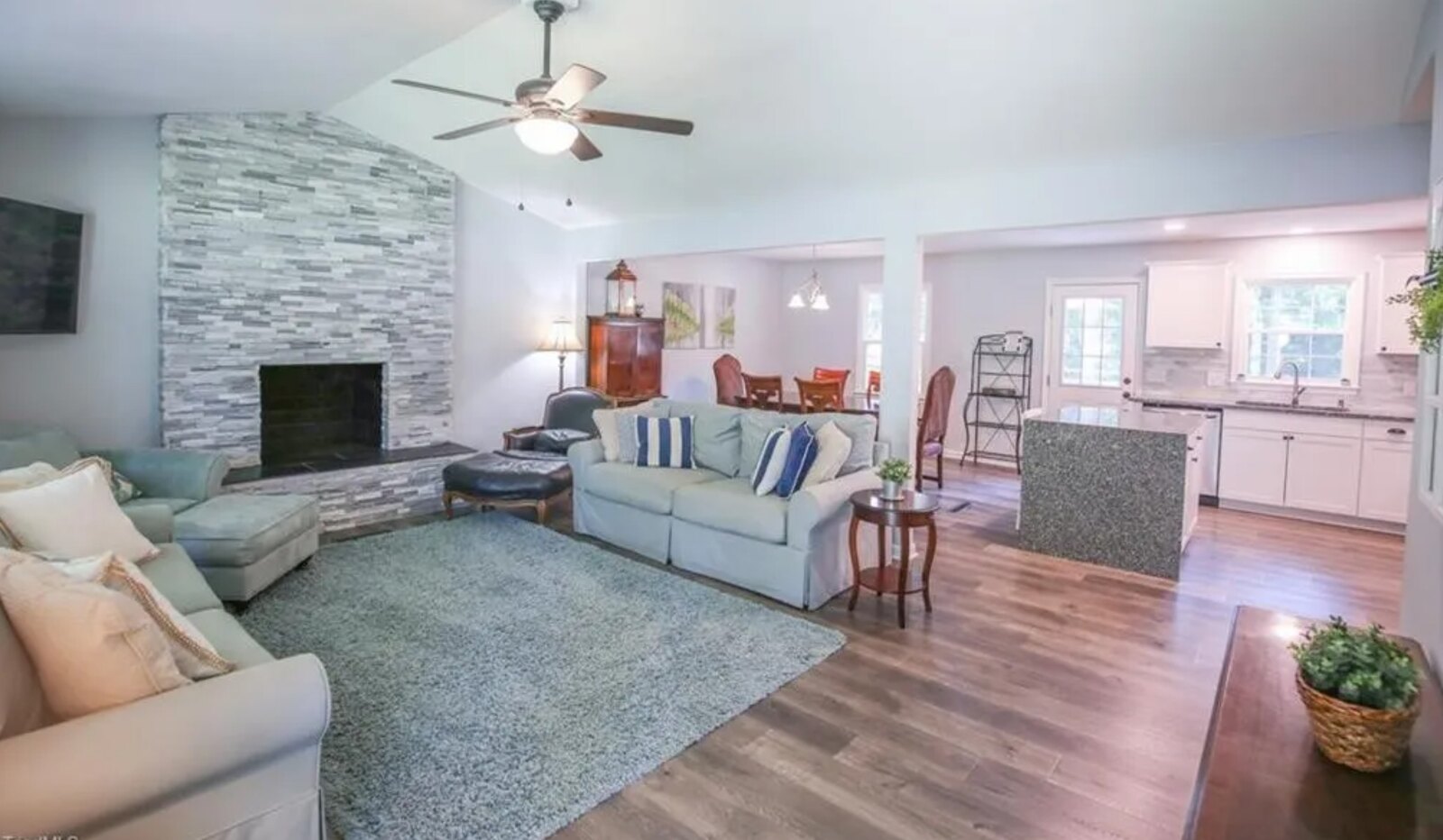 Living room with stacked stone fireplace, hardwood floors and modern staging by Alex's Home Innovations